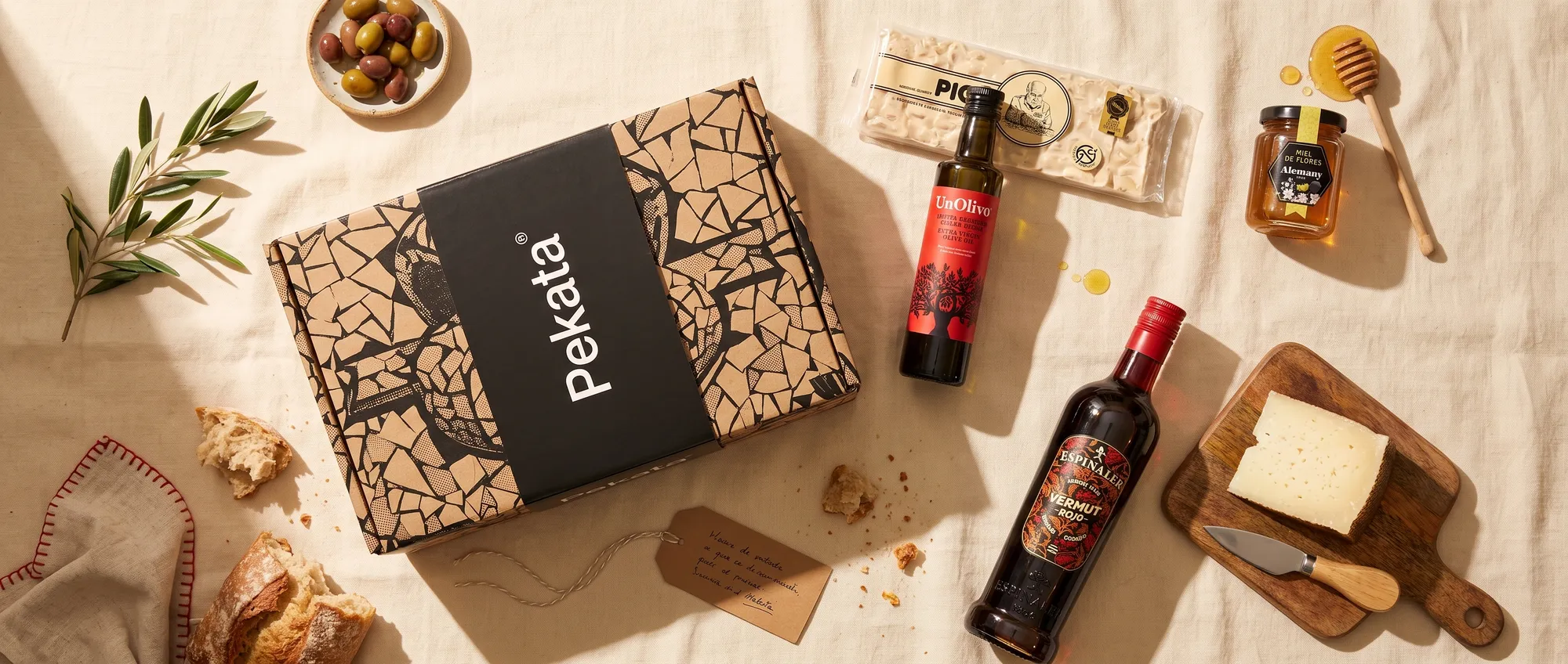 Pekata-Weihnachtsbox mit handwerklichem Turrón, Honig, Olivenöl und Wermut auf einem Tisch